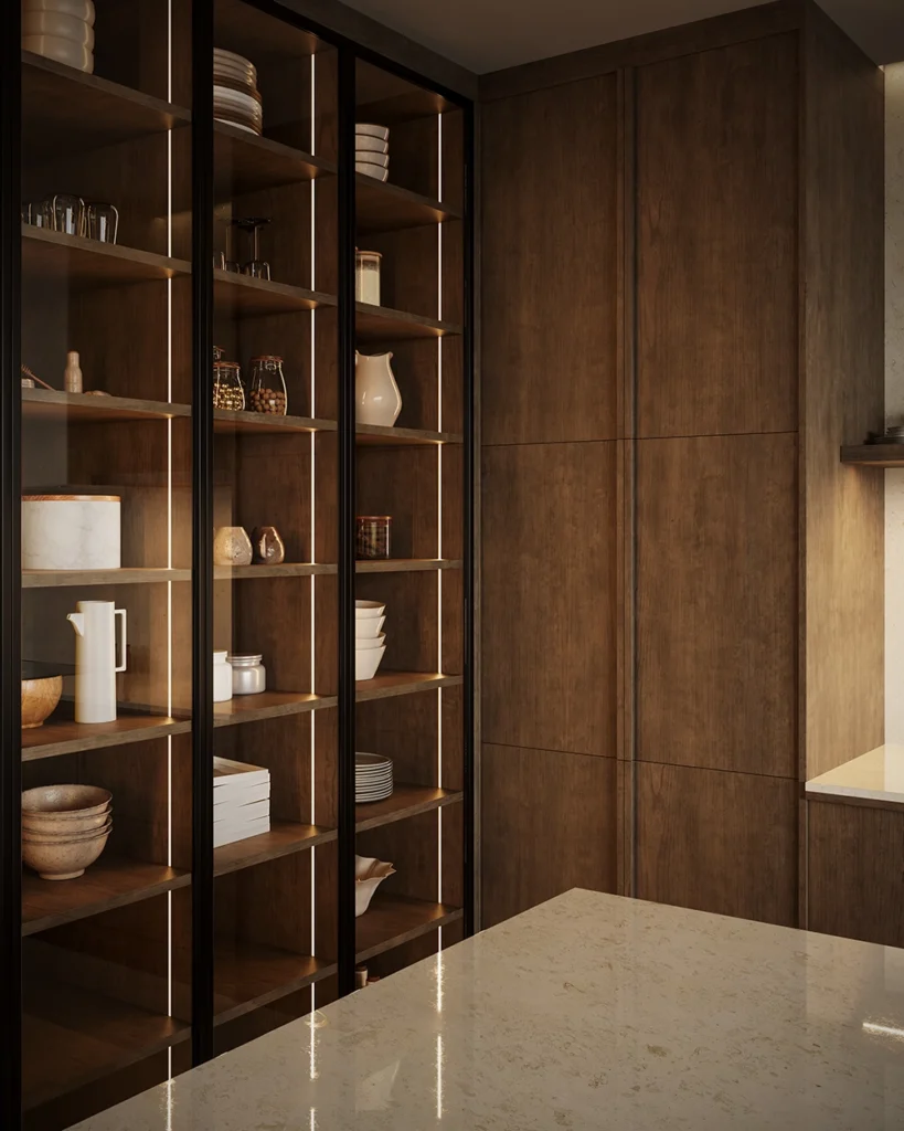 Close-up of Elmwood dark wood cabinetry with black-framed glass doors and Häfele integrated vertical LED lighting highlighting shelves and stone countertop.